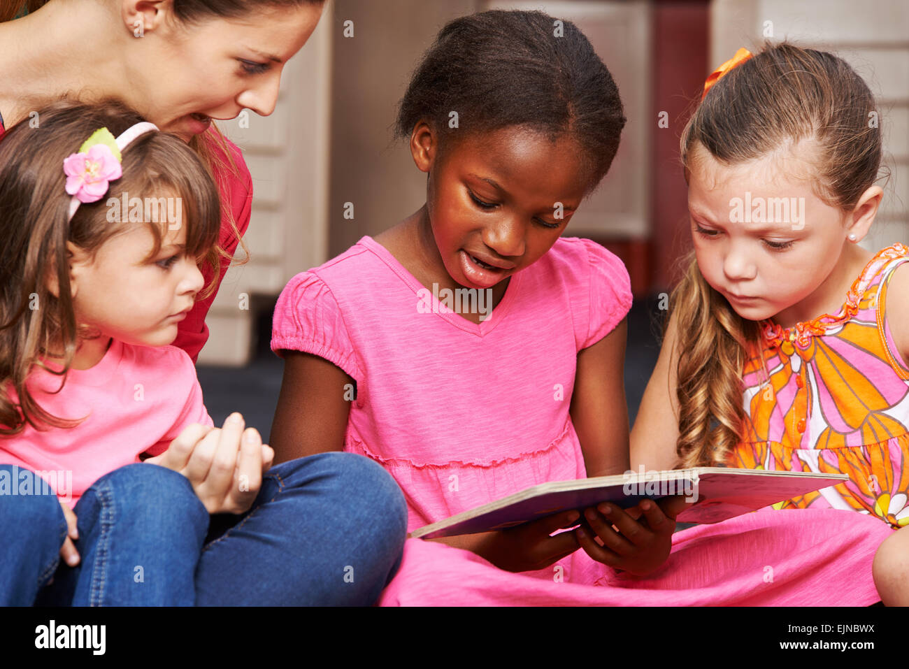 Children learning to read with nursery teacher in preschool Stock Photo