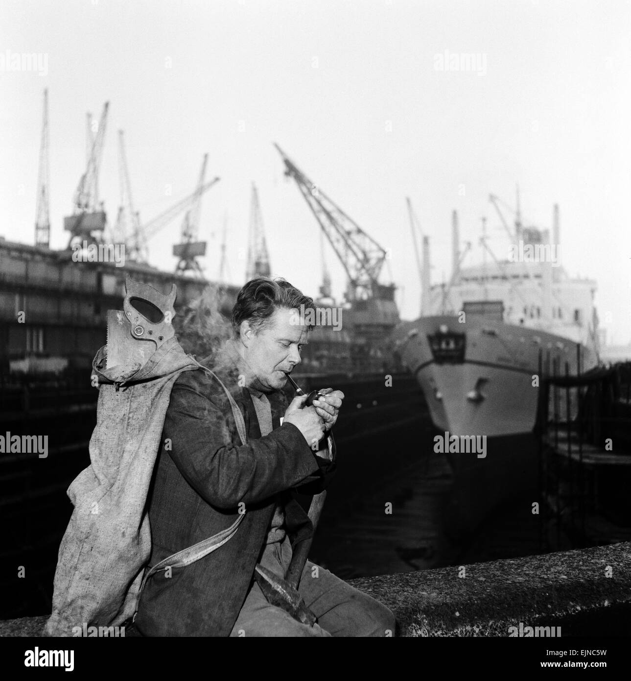 Unemployed and views of Liverpool, Merseyside, 30th November 1962. Carpenter lights his pipe down at the docks. Stock Photo