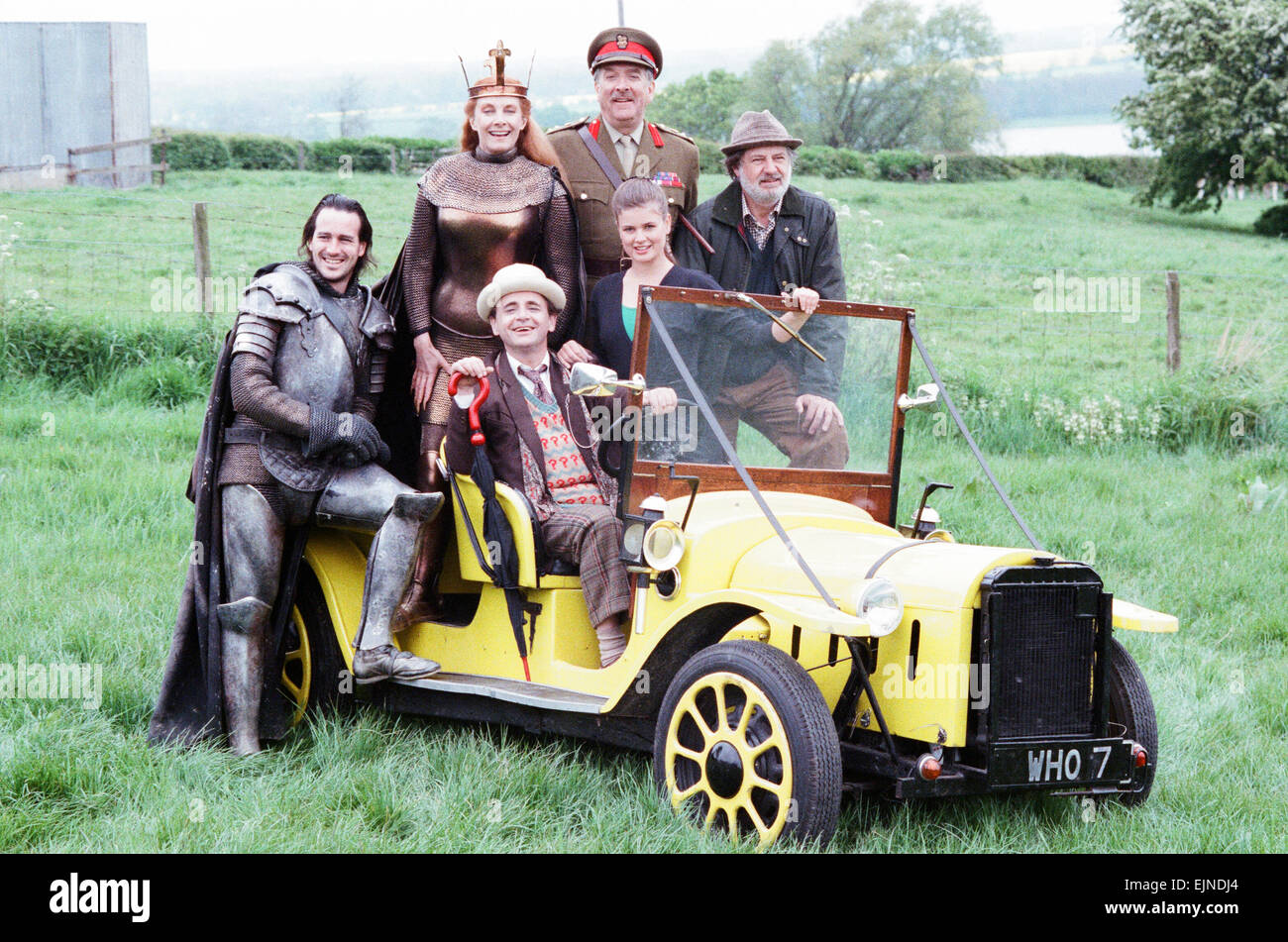 Sylvester McCoy as the Doctor behind the wheel, Christopher Bowen as Mordred (suit of armour) Jean Marsh as Morgaine (wearing crown), Nicholas Courtney as Brigadier Lethbridge Stewart (military uniform) James Ellis as Peter Warmsley (Pork pie hat)and Sophie Aldred as Ace pose with the Doctor's car Bessie whilst on location filming for the Dr Who story Battlefield. 16th May 1989 Stock Photo