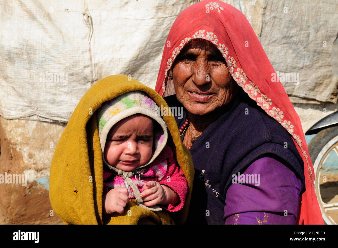 Elderly Rajisthani woman holds a little baby girl in a shawl kalpi Tribal Village Rajasthan India Stock Photo