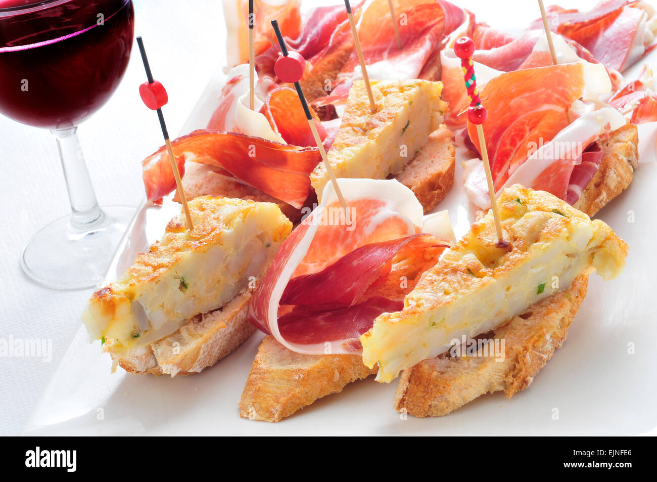 closeup of a plate with some typical spanish pincho de tortilla and pincho de jamon, spanish omelete and serrano ham served on b Stock Photo