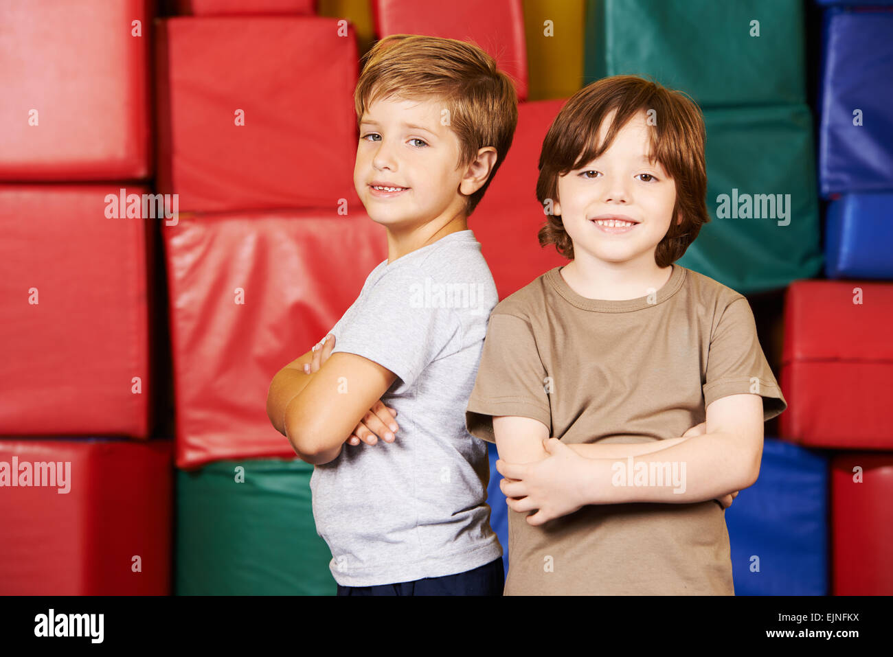 Two friends standing with their arms crossed in gym of preschool Stock Photo Alamy