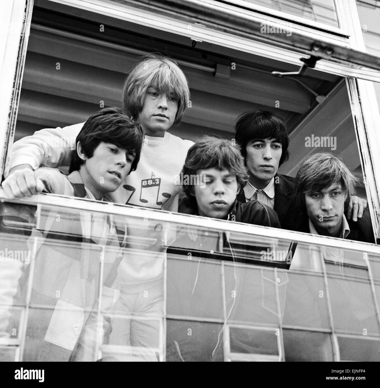 The Rolling Stones looking out of a window at female fans after