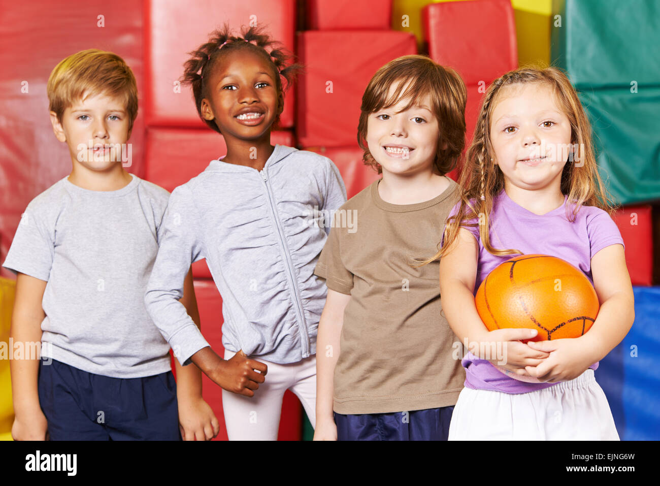Smiling kids team standing with ball in a gym of a preschool Stock Photo