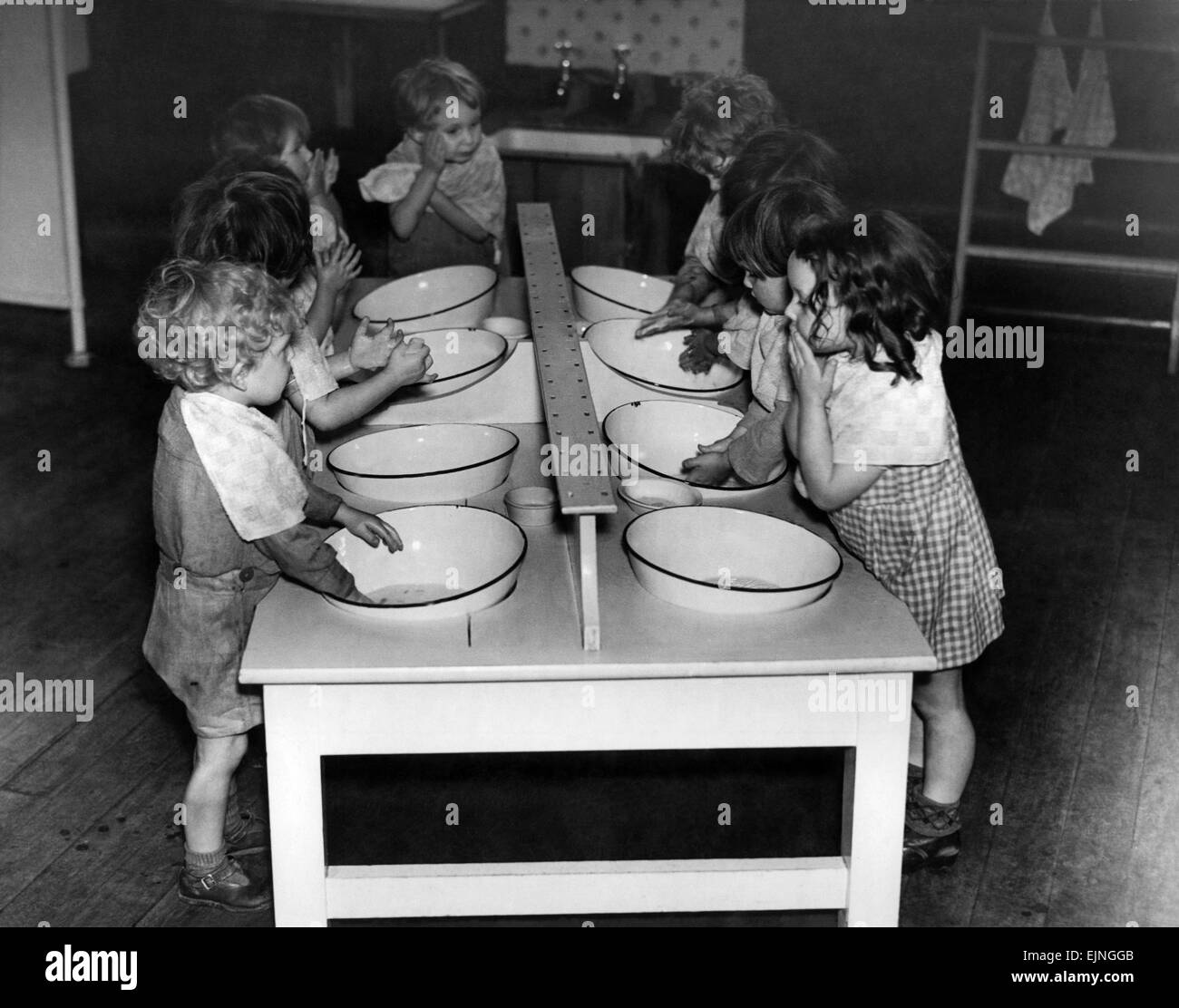 Young children washing themselves in enamal basins during World War Two. November 1943 Stock Photo