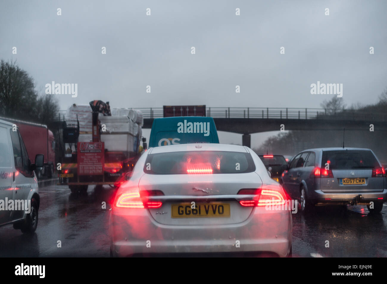 dreary wet rush hour journey standstill on motorway carriage stationary cars lorries with tail rear brake lights low visibility Stock Photo