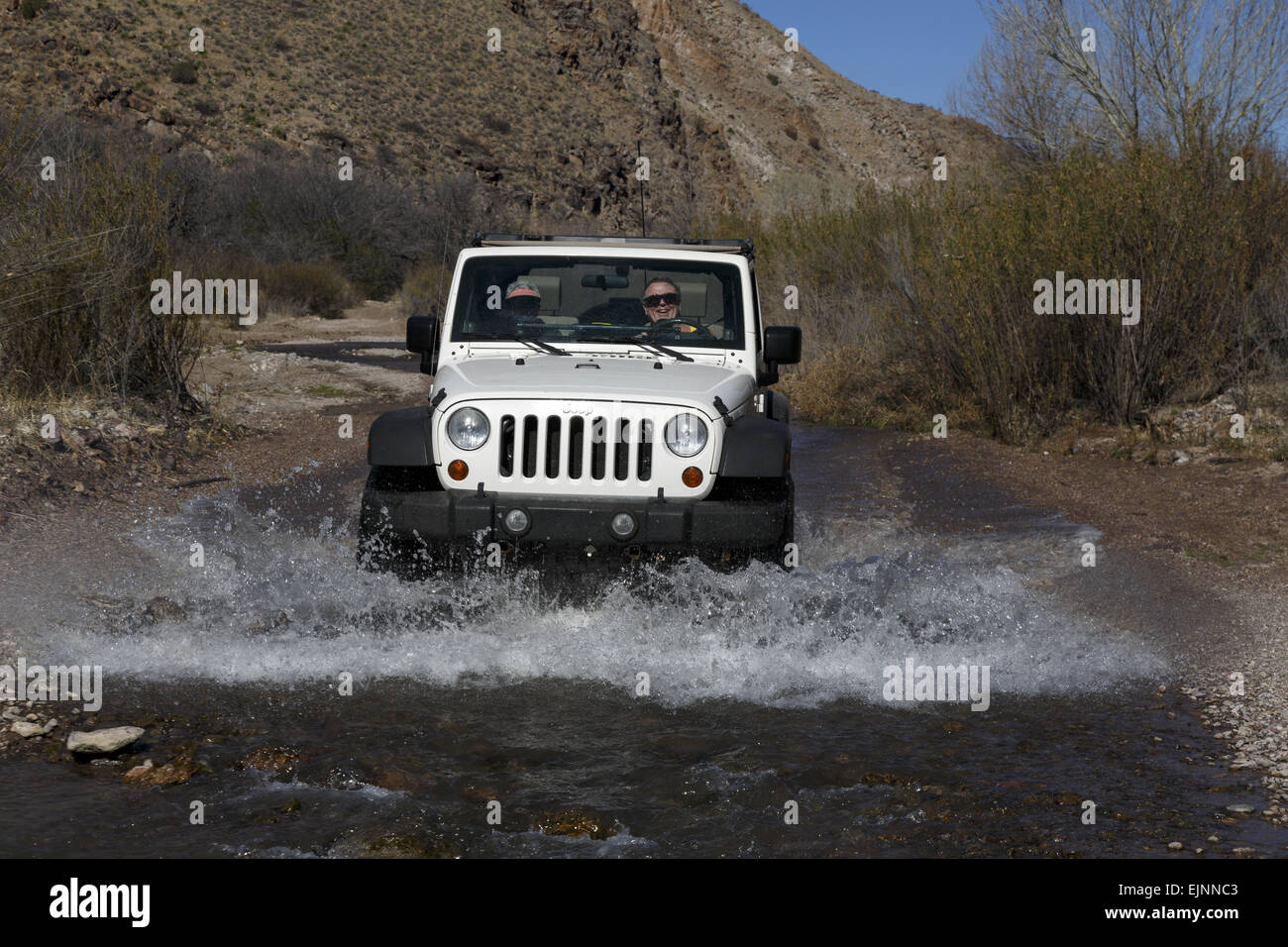 Jeep creating spray driving through water in Monticello Box Canyon New Mexico USA front view