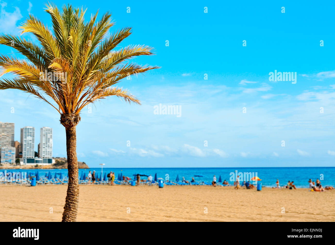 a view of Levante Beach, in Benidorm, Spain, with blurred vacationers hanging out on the sand in the background Stock Photo