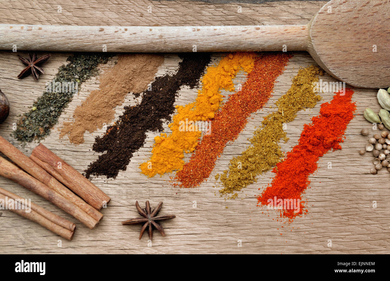 bands of different spices powder, anise and cardamom and spoon on wood background Stock Photo