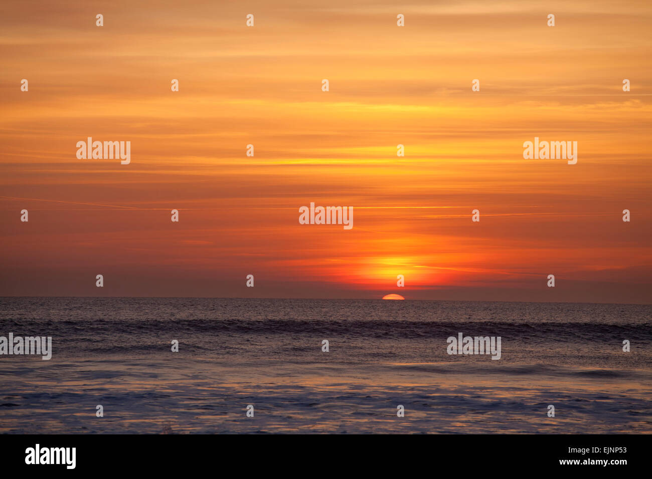 Sun setting beneath the horizon of the sea, Saunton Sands, North Devon Stock Photo