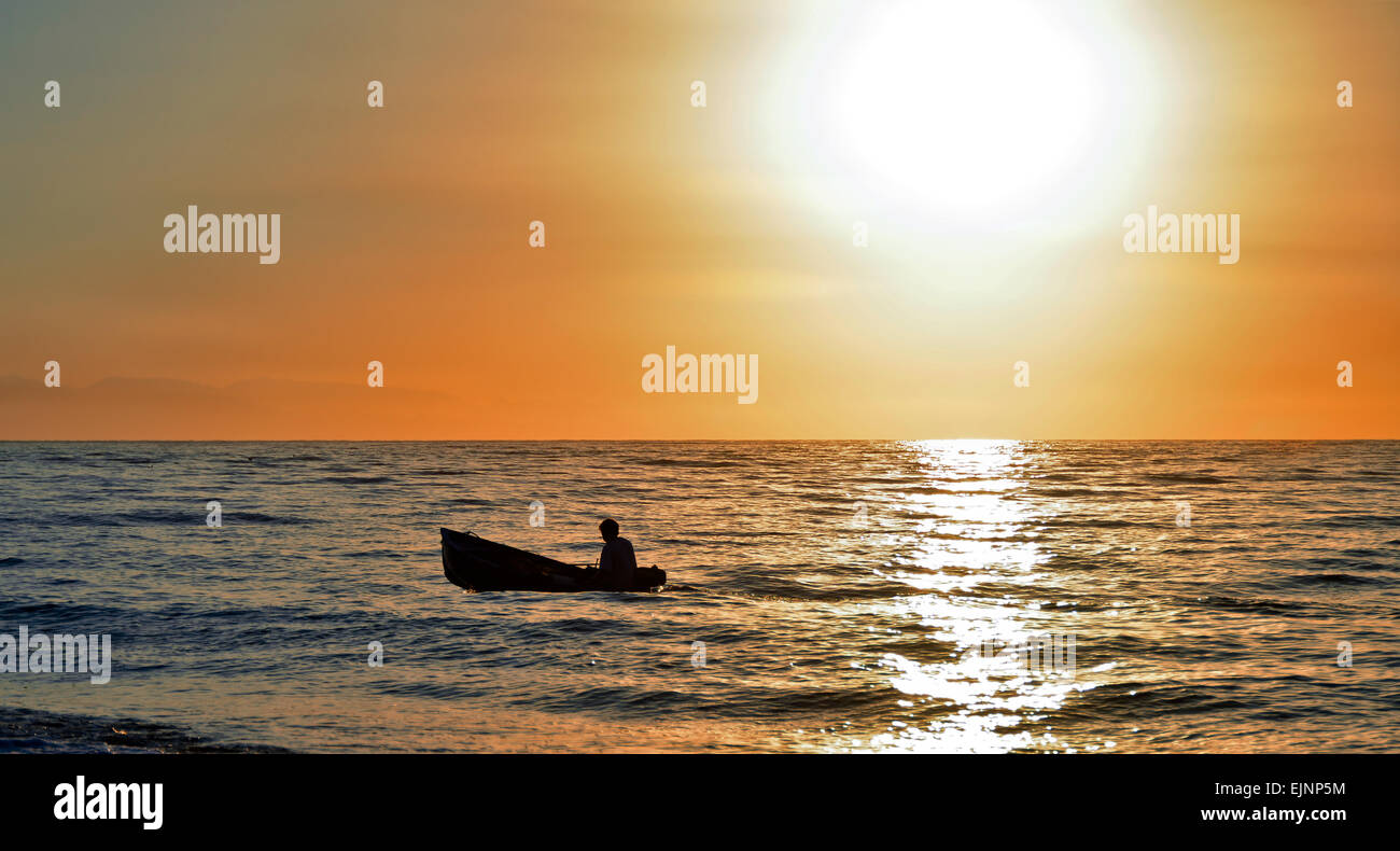 Silhouette of a little fishing boat on sunset Stock Photo - Alamy
