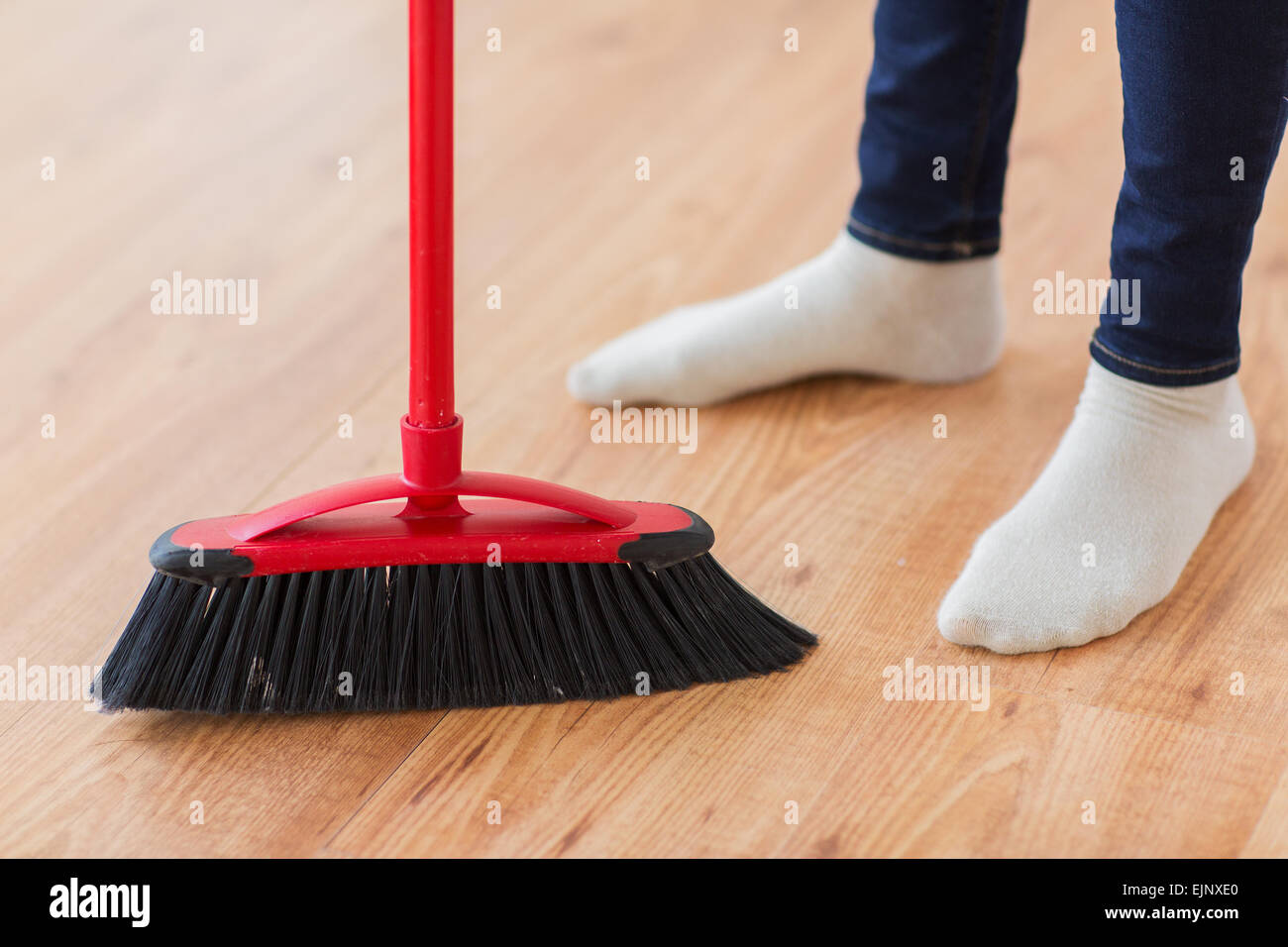 Close Up Of Woman Legs With Broom Sweeping Floor Stock Photo