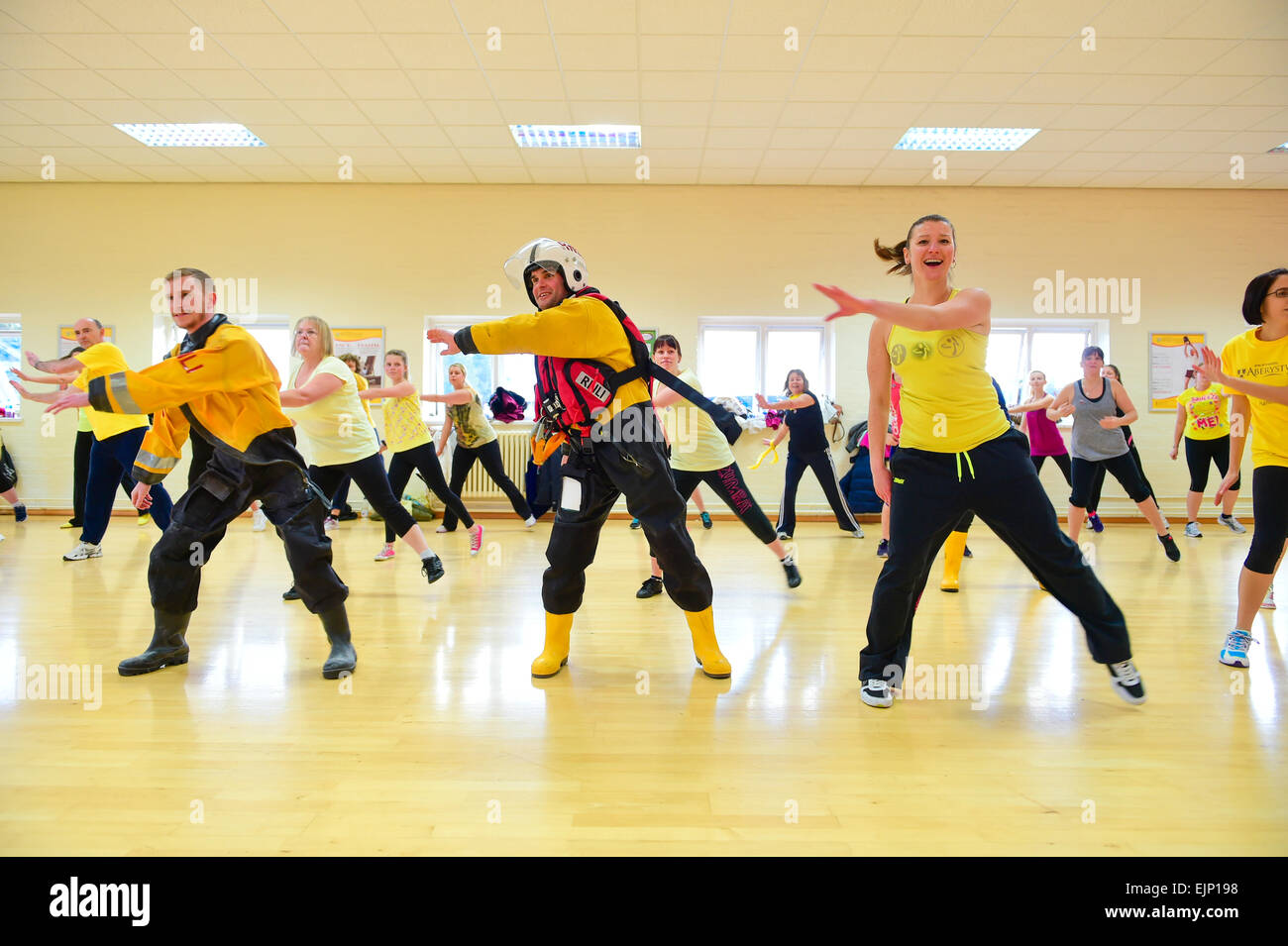 Two male crew members in full immersion survival kit taking part in a 'Zumbathon' fund raising event at Aberystwyth University sports  centre in aid of the Royal National Lifeboat institution (RNLI) Stock Photo