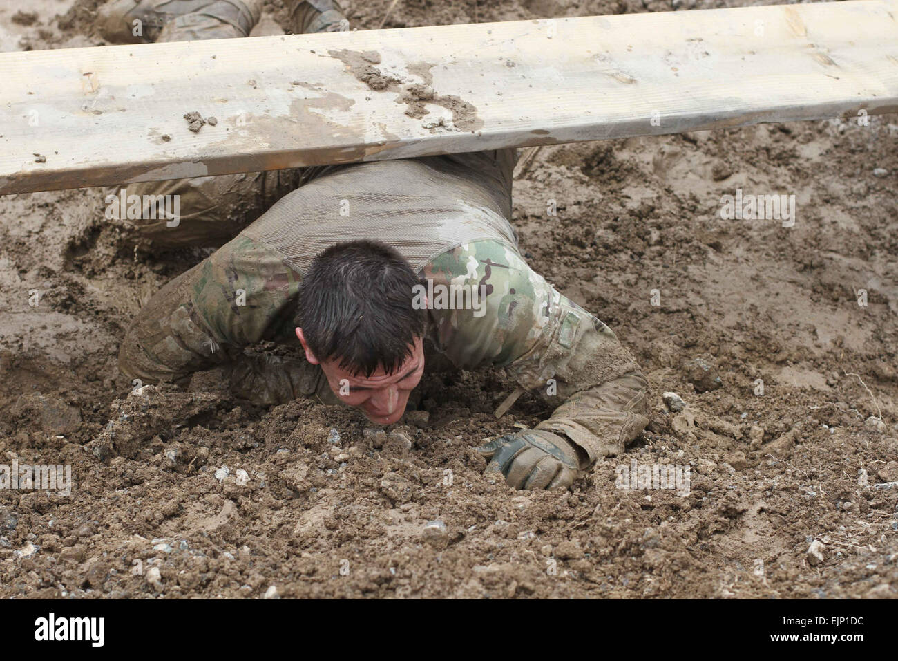 A Soldier manages the over-and-under obstacle while participating in the Forward Operating Base Salerno, Afghanistan, Mud Run, March 24, 2013. More than 50 soldiers from various units from the FOB participated in the course. The two-mile course featured 15 different obstacles that challenged the soldiers physically and mentally, while adding the elements of water and mud to help make the course even more difficult.  Sgt. 1st Class Abram Pinnington, TF 3/101 Public Affairs Stock Photo