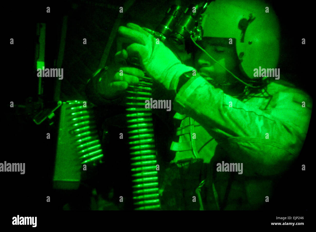 As seen through a night-vision device, U.S. Army Spc. Isaiah Holt, 10th Mountain Division, 3rd Battalion, 10th General Support Aviation Battalion, 10th Combat Aviation Brigade, loads ammunition into his 240B machine gun as he prepares for night missions on Forward Operating Base Fenty in Nangarhar province, Afghanistan, July 22, 2013.  Staff Sgt. Jerry Saslav Stock Photo