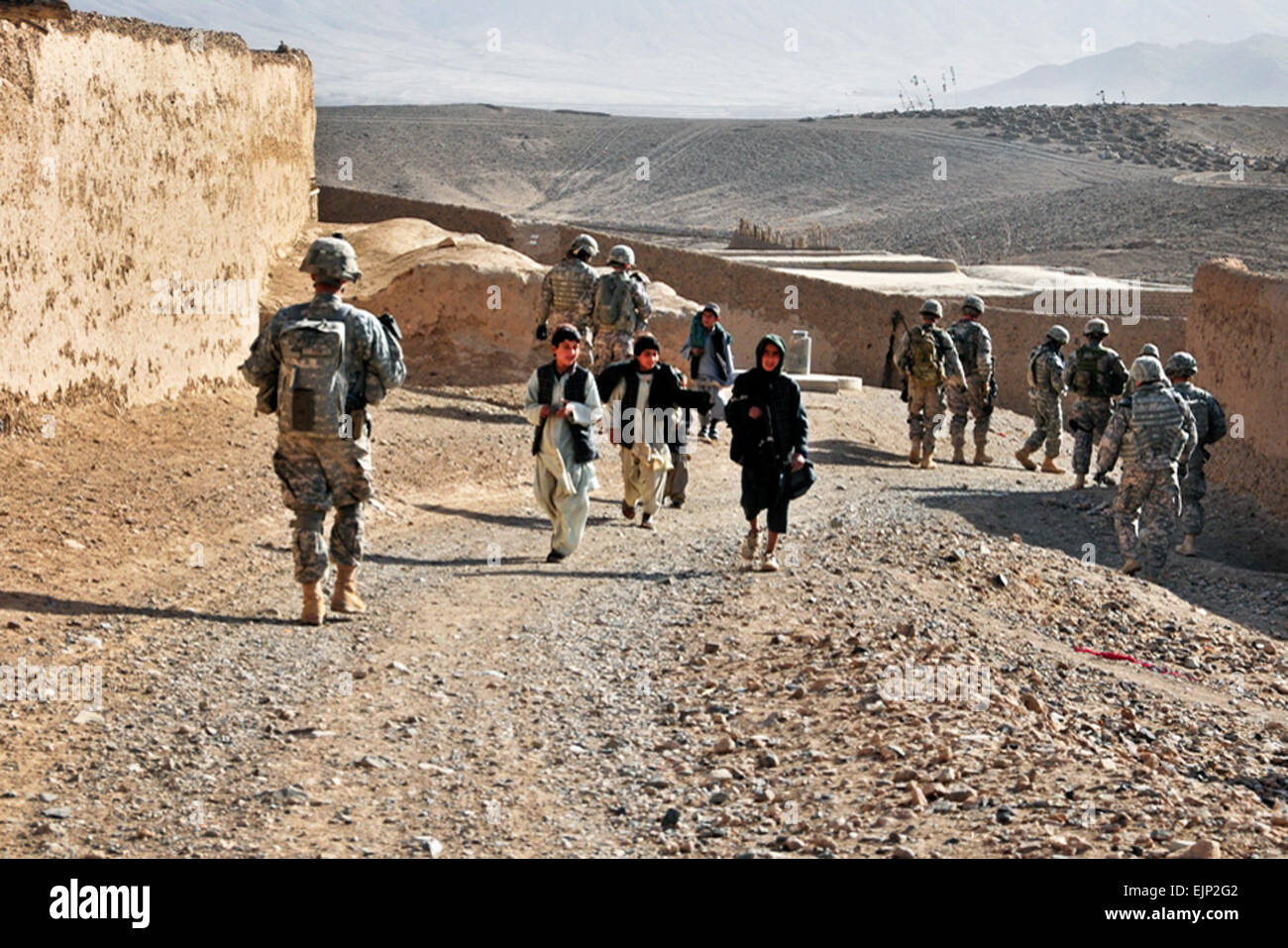 U.S. Army soldiers pass by children while on patrol near Sha Wali Kot in Uruzgan province, Afghanistan, Feb. 16, 2011. The soldiers are assigned to the 2nd Stryker Cavalry Regiment. U.S. Army photo Stock Photo