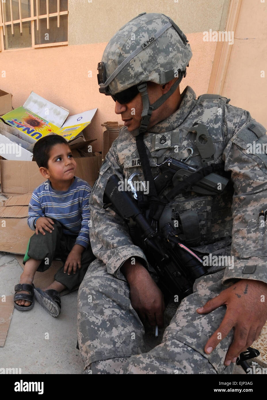U.S. Army Staff Sgt. Samson Barini, assigned to Charlie 422nd Civil Affairs Battalion, tries to communicate with a small Iraqi boy, as they sit in the court yard of the Manara primary school, north of Mosul, Iraq, Oct. 24. Barini and U.S. Soldiers assigned to Alpha   Company, 2nd of the 82nd Field Artillery, 1st Cavalry Division, 3rd Brigade, distributed more than 600 backpacks during a humanitarian-aid  mission. Stock Photo
