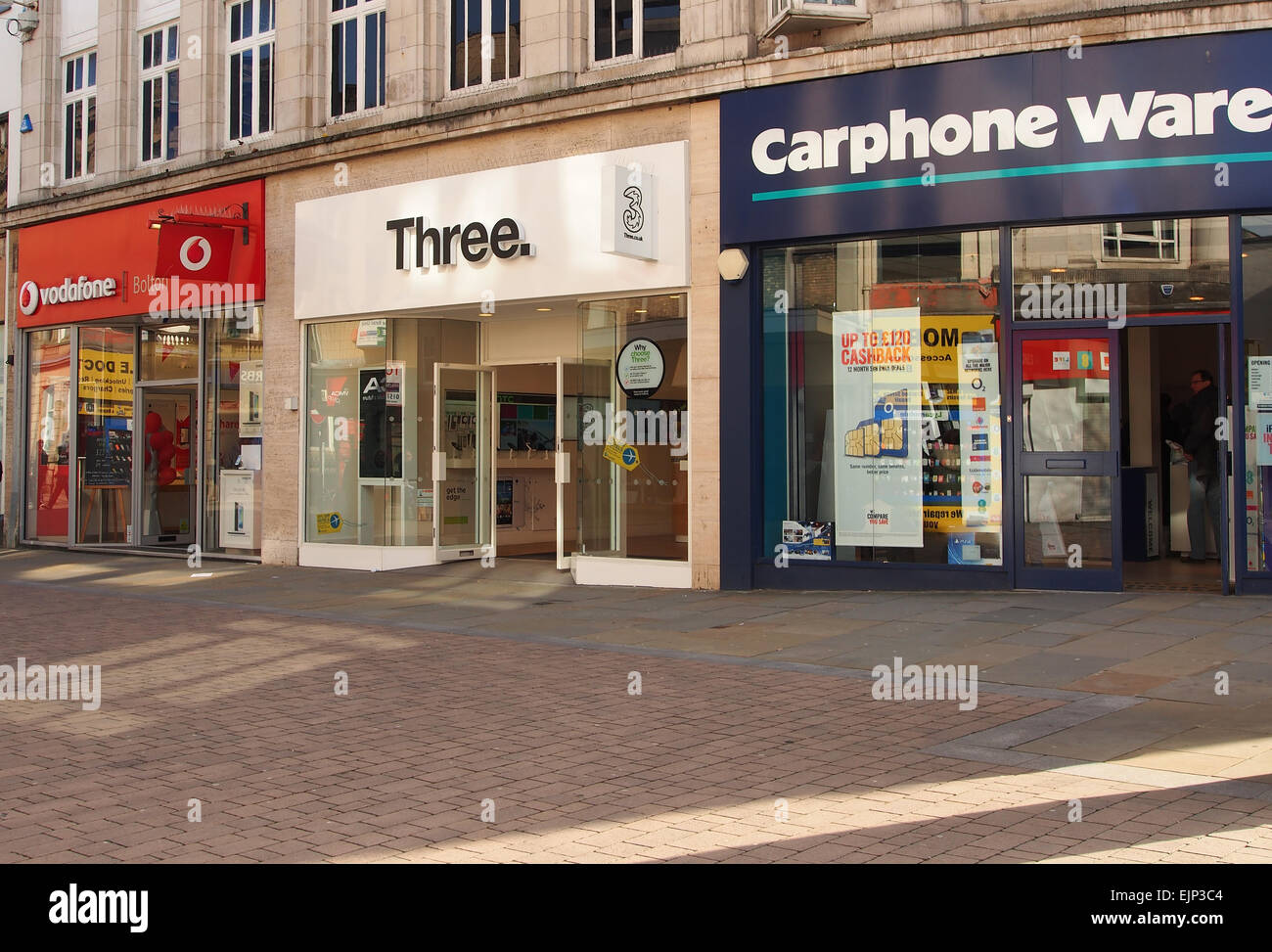 Shops selling mobile phones - Vodaphone, Three and Carphone Warehouse all together on a Bolton street Lancashire, UK. Stock Photo