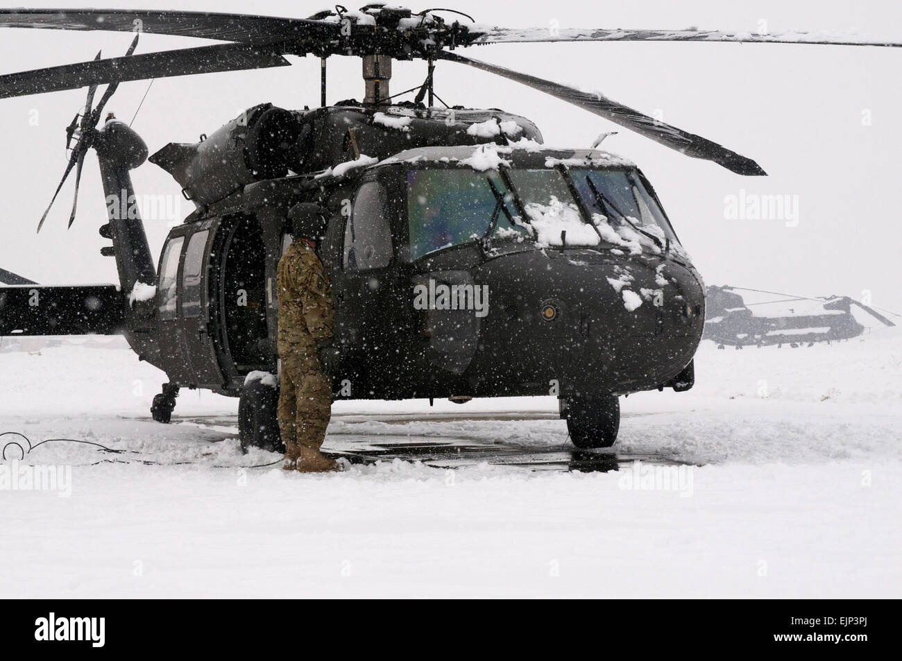 Spc. Rodney Pentecost, a Task Force Talon crew chief from Greens Fork, In., assist pilots while they run through pre-flight checks during a snow storm on Bagram Airfield, Afghanistan, Jan 22.  This is the second major snow storm to hit Bagram this year, and is expected to continue for a few days.  Sgt. 1st Class Eric Pahon, Task Force Poseidon Public Affairs Stock Photo