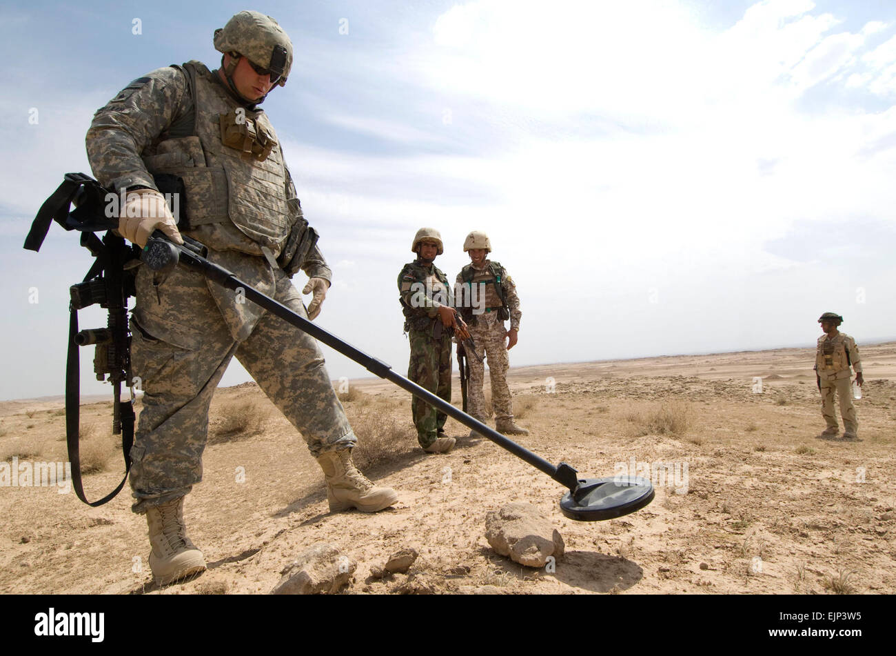 U.S. Army Sgt. Brian Mueller, 1st Battalion, 24th Infantry Regiment, 1st Stryker Brigade Combat Team, 25th Infantry Division, checks a suspicious rock pile with a metal detector during a presence patrol in the area around Albu Sawwat, Iraq, on April 3. Stock Photo