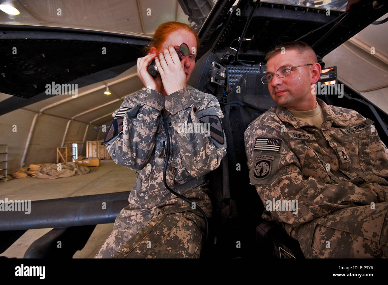 Camp Taji, Iraq, Aug 10, 2009- While going through various components of an AH-64D Apache attack helicopter, 1st Lt. Carolyn Wagnild left, from Boise, Idaho, an Apache pilot in Company C, 1st Battalion, 227th Aviation Regiment, 1st Air Cavalry Brigade, 1st Cavalry Division, explains how the sighting system of the Apache works to Sgt.1st Class Jonathan Duffey, from Troy, Ohio, the tactical operations center noncommissioned officer in charge for 2nd Battalion, 107th Cavalry Regiment of the Ohio National Guard. The meeting between the two units is meant to build trust and understanding between th Stock Photo