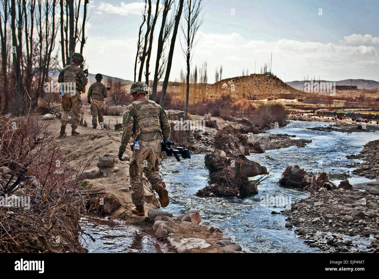 Soldiers from Company A, 2nd Battalion, 28th Infantry Regiment, Task Force 3-66th, navigate narrow causeways along a river bank in the village of Marzak. Marzak has historically been a stronghold for the insurgency over the past decade until the Afghan and U.S Forces took advantage of the winter months to establish a local police force and secure the village from foreign fighters who transit the area during the fighting season.  Staff Sgt. Charles Crail, 172nd Infantry Brigade, Task Force Blackhawk Stock Photo