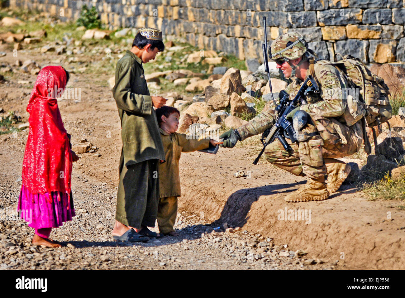 U.S. Army Cpl. Brian Lewis, a native of Duluth, Minn., and team leader assigned to 501st Infantry Regiment, 4th Brigade Combat Team Airborne, 25th Infantry Division greats an Afghan boy while conducting a security patrol in Shaway Valley, June 2. Blackfoot Company, stationed at Combat Outpost Chergataw, routinely patrols the valley in efforts to bring stability to the region.  Staff Sgt. Jason Epperson Stock Photo