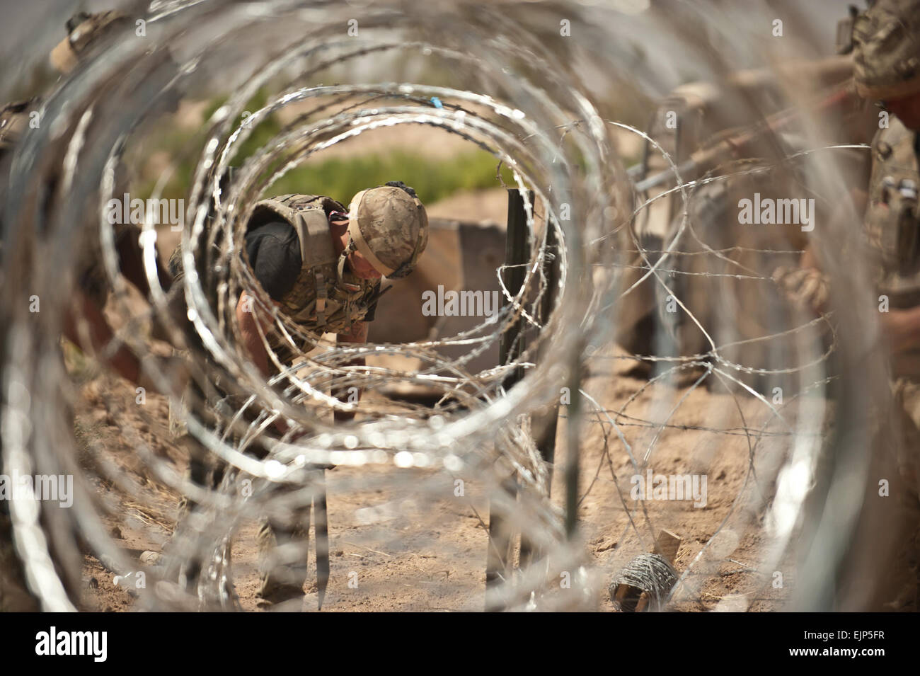 An engineer assigned to 59 Commando Squadron, Royal Engineers, secures concertina wire for a security barrier in Lashkar Gah District, Helmand province, July 25. The Engineers built the station for the Afghan Local Police, a local security force made up of handpicked individuals from the community. Stock Photo