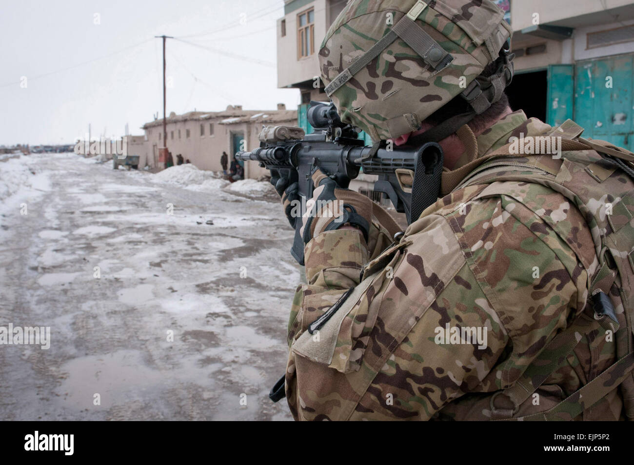 U.S. Army Staff Sgt. Tom Maahs, from Maple Shade, N.J., who is with the Task Force Paladin explosive ordinance disposal unit, inspects the site of an IED through his rifle scope on a street near the wood market in Gardez, Feb. 18. The IED was discovered by local Afghan Uniformed Police and later destroyed by an Afghan National Army explosive ordinance disposal unit. Stock Photo