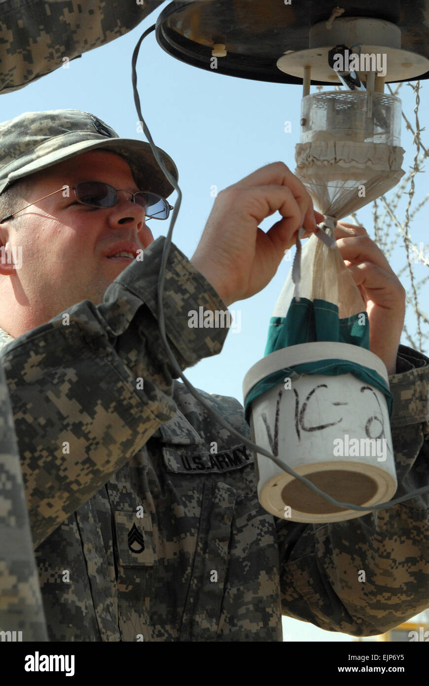 Staff Sgt. Seth Odette, 1848th Medical Detachment's preventative medicine section, removes the collecting unit from a Center for Disease Control miniature light trap. The trap uses an ultraviolet light and a small fan to trap mosquitoes, sand flies and other flying insects. Stock Photo