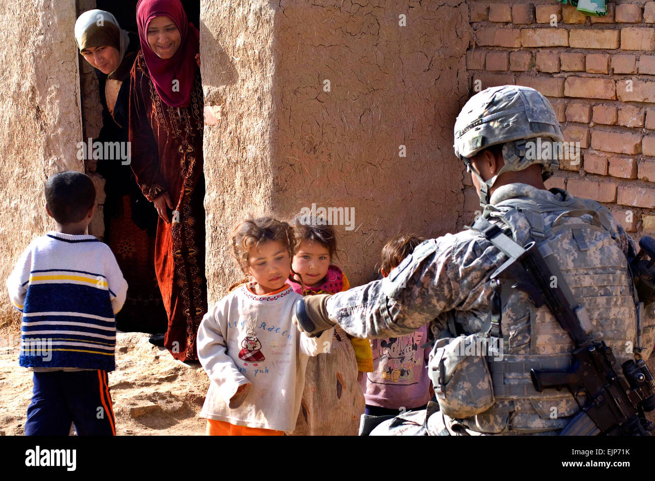 Iraqi children receive candy from U.S. Army Sgt. Anthony Woods from 1st Battalion, 2nd Infantry Regiment attached to 3rd Battalion, 66th Armor Regiment, 1st Stryker Brigade Combat Team, 25th Infantry Division, during the clearing of the village of Tammuz, in Diyala Province, Iraq, on March 2, 2009.  Mass Communication Specialist 2nd Class Walter J. Pels Stock Photo