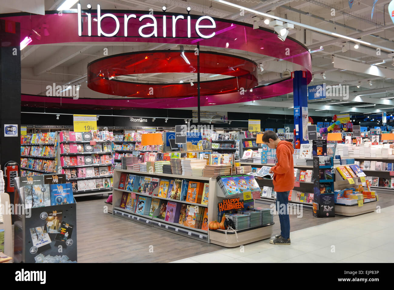 BELGIUM - OCTOBER 2014:  Boy is reading a comic book at the librairie section in a Carrefour hypermarket in Belgium Stock Photo