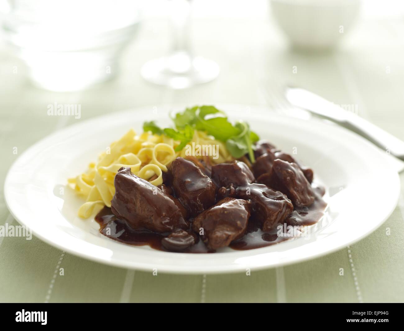 Beef in gravy casserole with linguine and roquette leaves Stock Photo