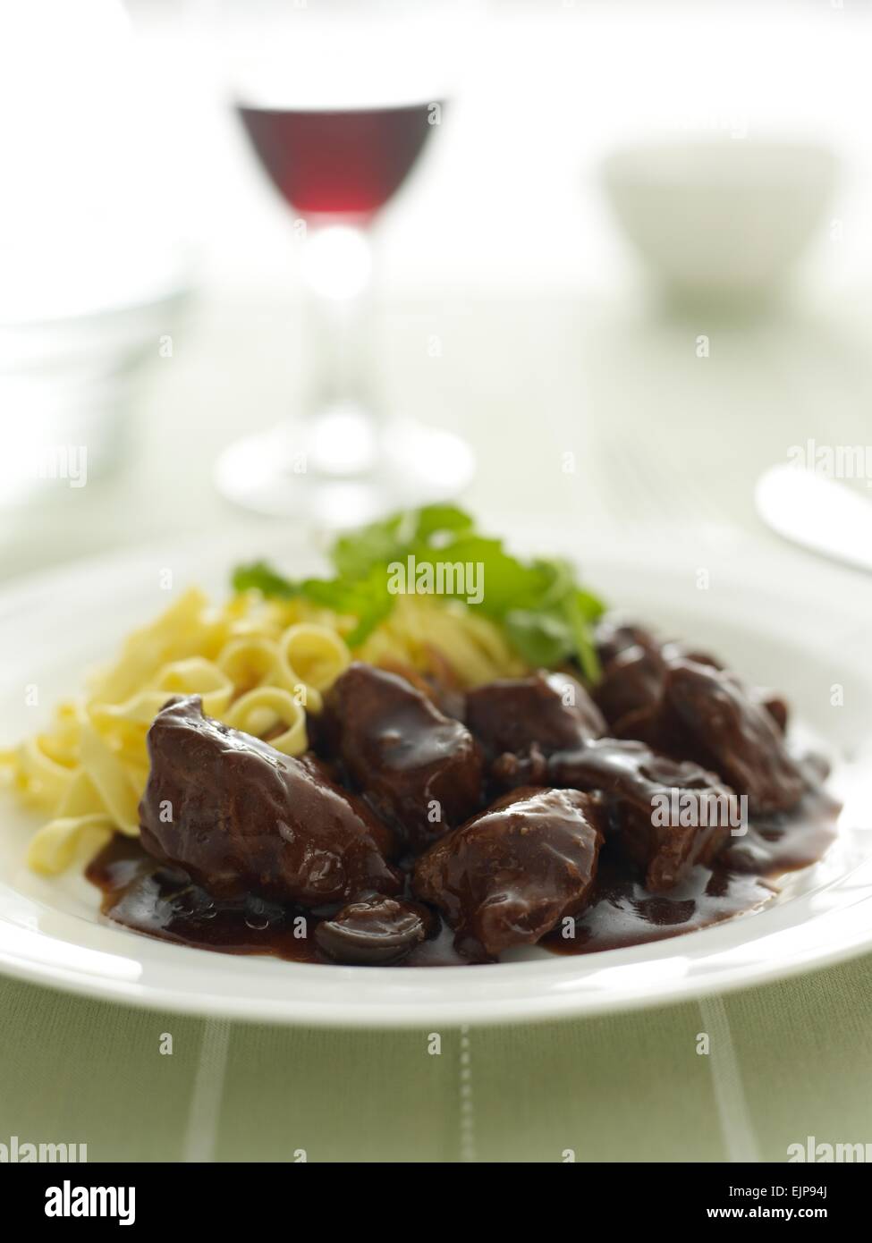 Beef in gravy casserole with linguine and roquette leaves Stock Photo
