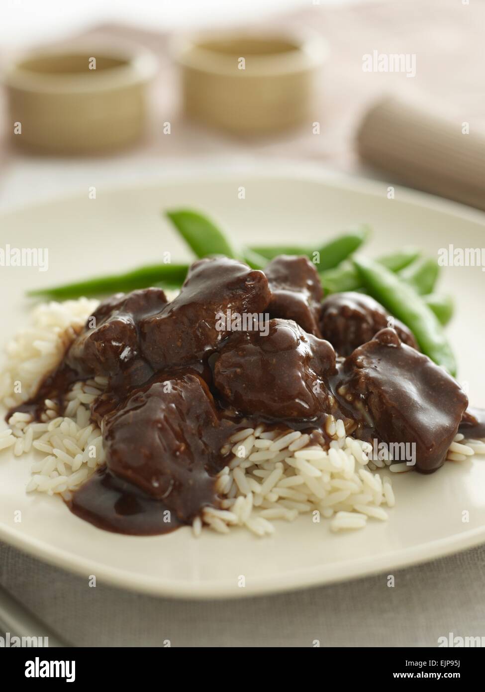 Meal of beef in gravy on rice with mange tout on a cream plate Stock Photo Alamy