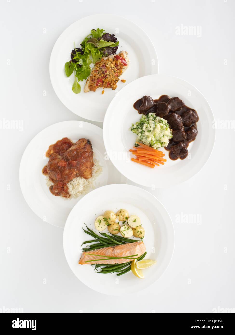 Aerial photograph of four plated meals Chicken provencal grilled salmon beef in gravy and chicken in red wine and mushroom sauce Stock Photo