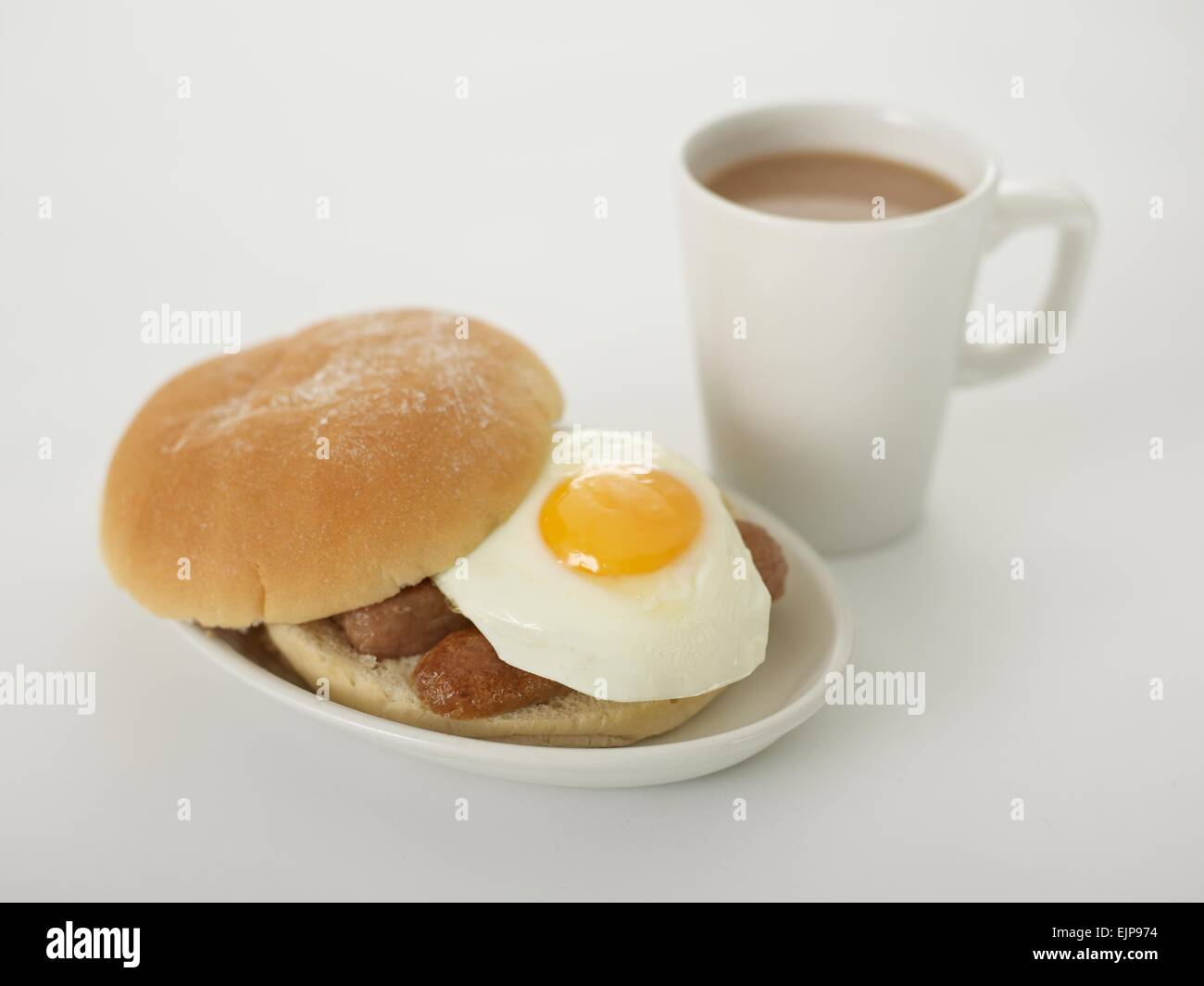 sausage fried egg bap bread bun floured breakfast mug of tea on a white background Stock Photo
