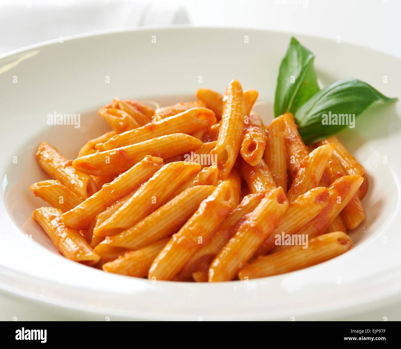 talian plain penne tubes of  pasta mixed with tomato and basil sauce Simple Dinner in a restaurant or care home healthy Stock Photo