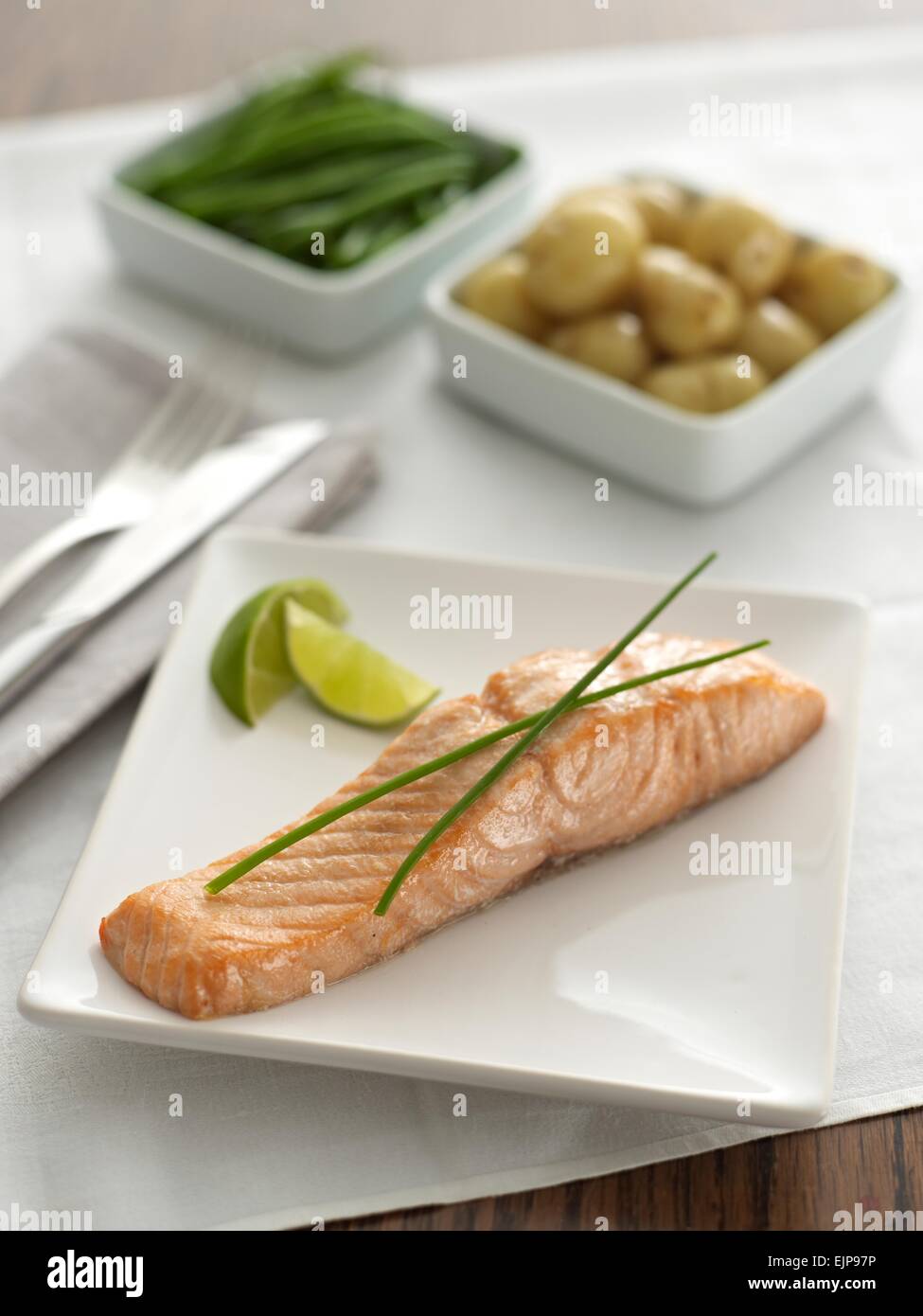 Simple plated meal of pan fried plain fillet salmon fish with lime chives and separate square dishes of vegetables Stock Photo