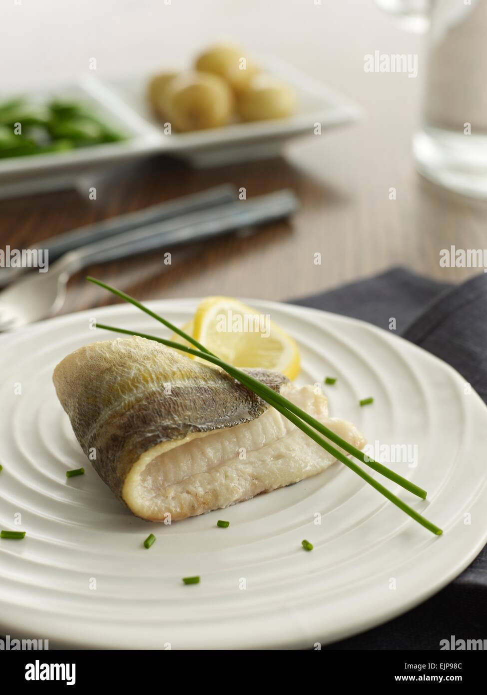 Simple plated meal of pan fried plain fillet of herring fish with lemon chives boiled new