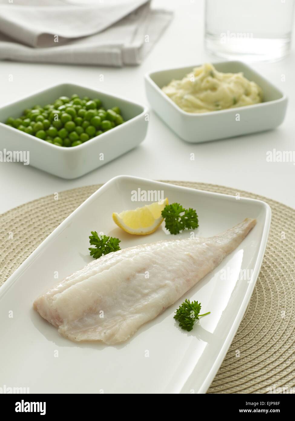 Plated meal of plain fillet of haddock fish with lemon parsley peas