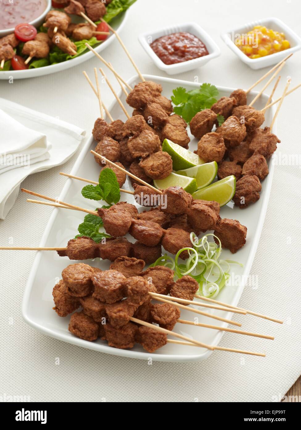 buffet plate of chicken pieces on wooden skewers with a sweet chilli