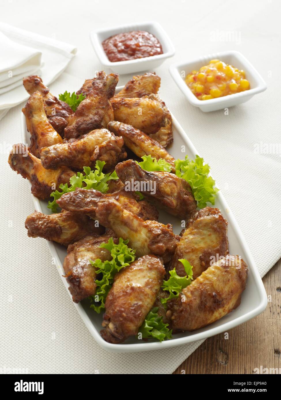 barbecued chicken pieces with skin on  with lettuce and dips. legs and wings.buffet Stock Photo