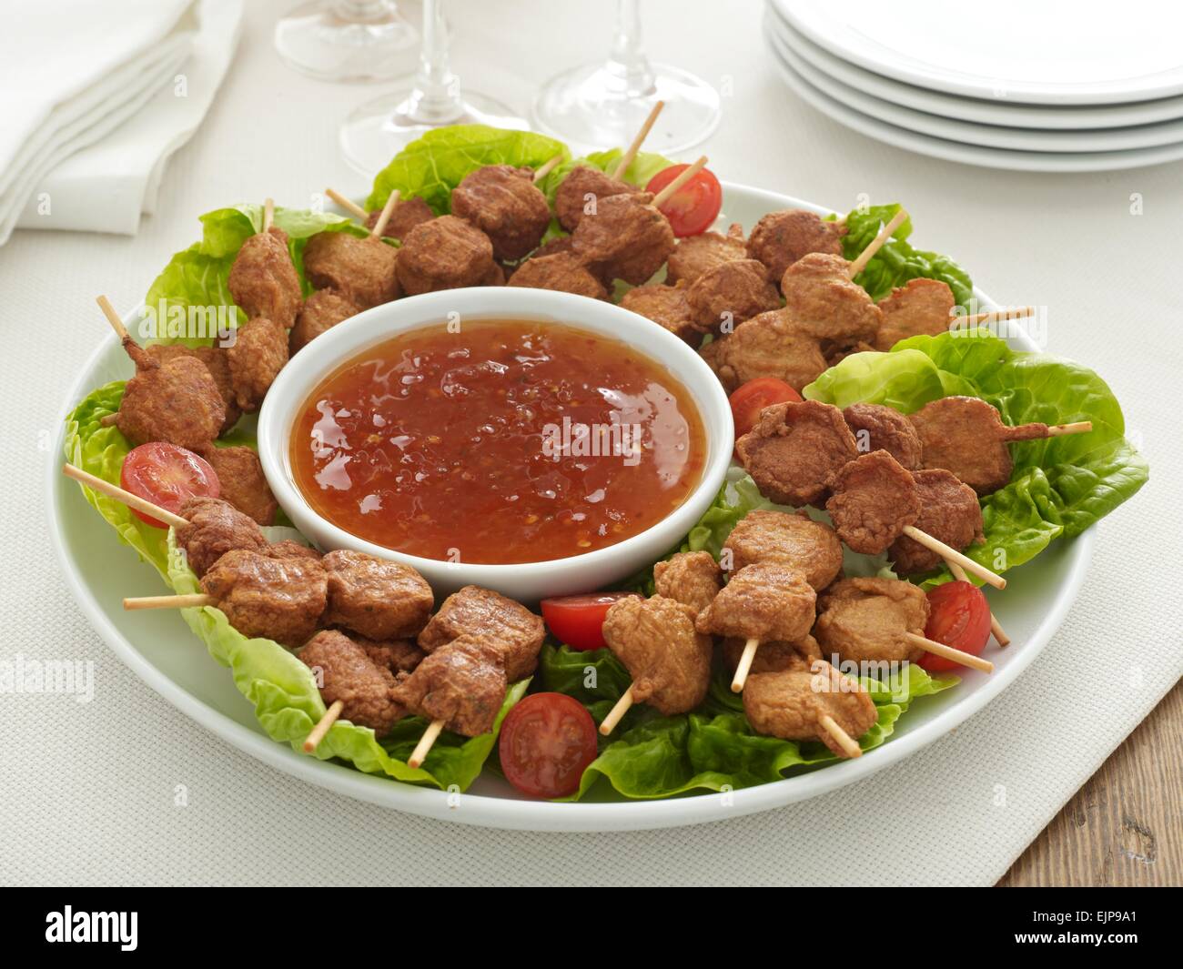 buffet plate of chicken pieces on wooden skewers with a sweet chilli