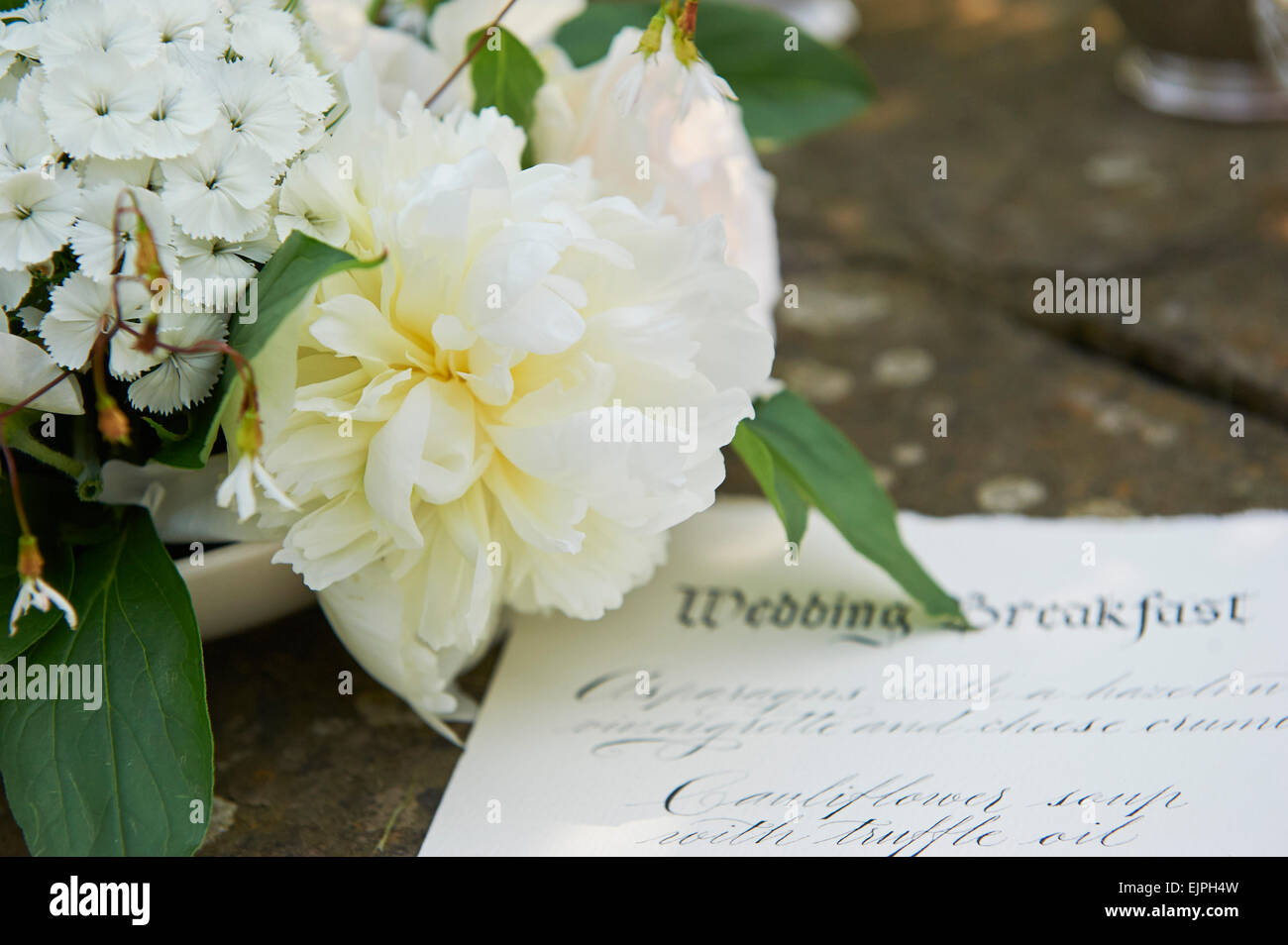 calligraphy menu on parchment with peonies from a styled wedding shoot
