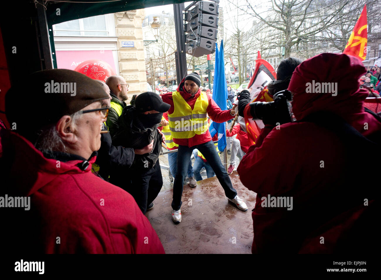 Brussels, Belgium. 30th Mar, 2015. A masked man tries to disrupt an union union leader's speech by storming the stage. -Thousands took part in an anti austerity demonstration organized by multiple workers' unions and political parties. Clash broke out as members of 'LCR' (Revolutionary Communist League of Belgium) tries to take over the stage. Credit:  Geovien So/Pacific Press/Alamy Live News Stock Photo