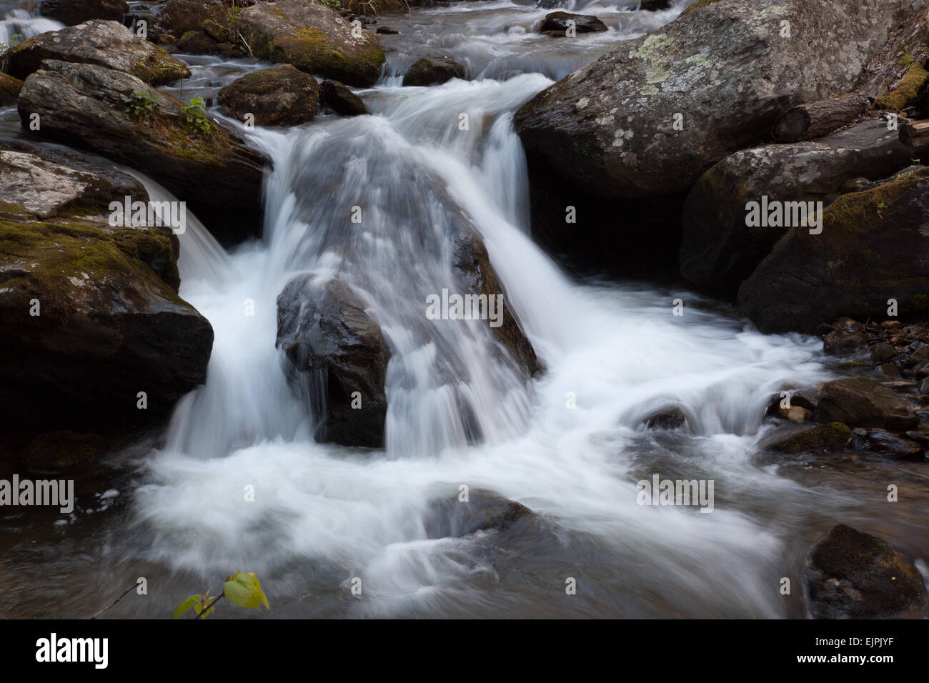 Water cascading by moss covered stones Stock Photo