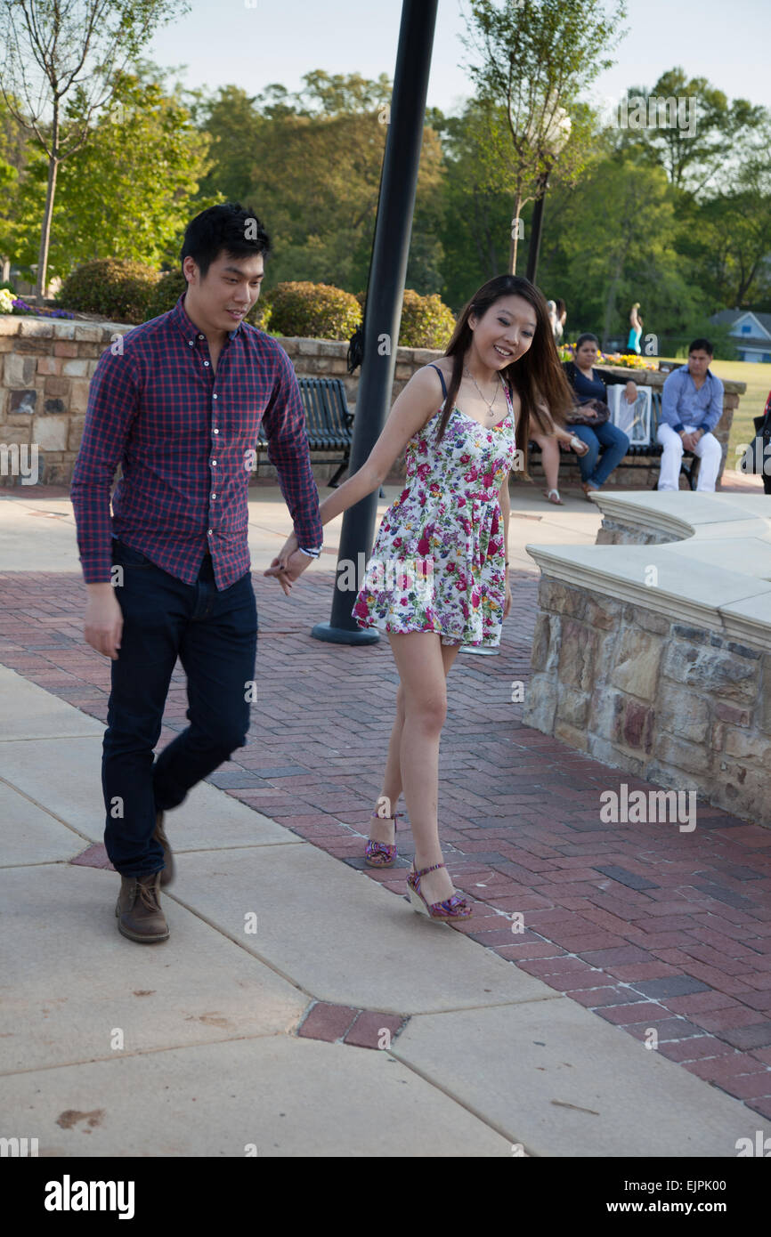 Happy Asian couple, a man and a woman, walking outdoors with smiles on their faces Stock Photo