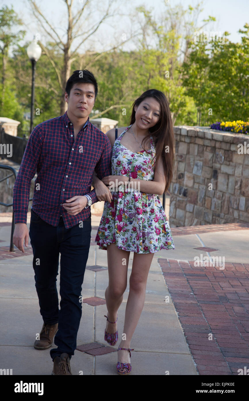 Happy Asian couple, a man and a woman, walking outdoors with smiles on their faces Stock Photo