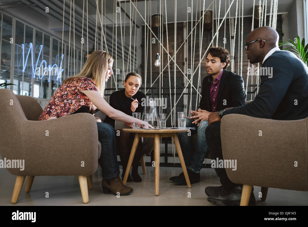 Diverse group of executives meeting in office sharing creative ideas. Young people having a meeting in lobby. Stock Photo